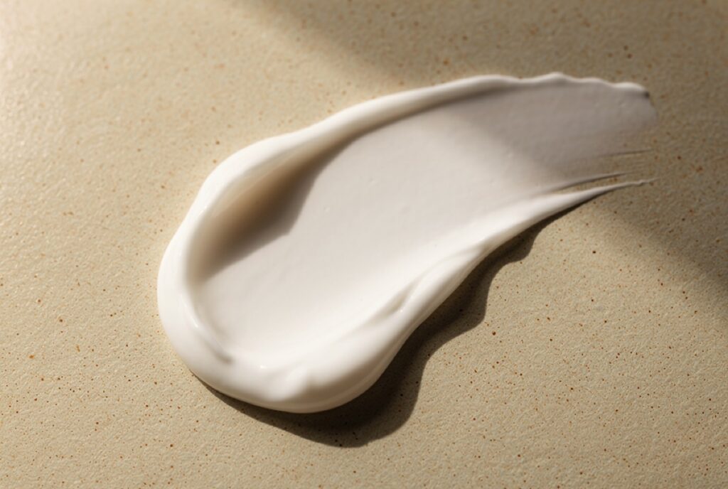 Rich face cream swatch on beige ceramic